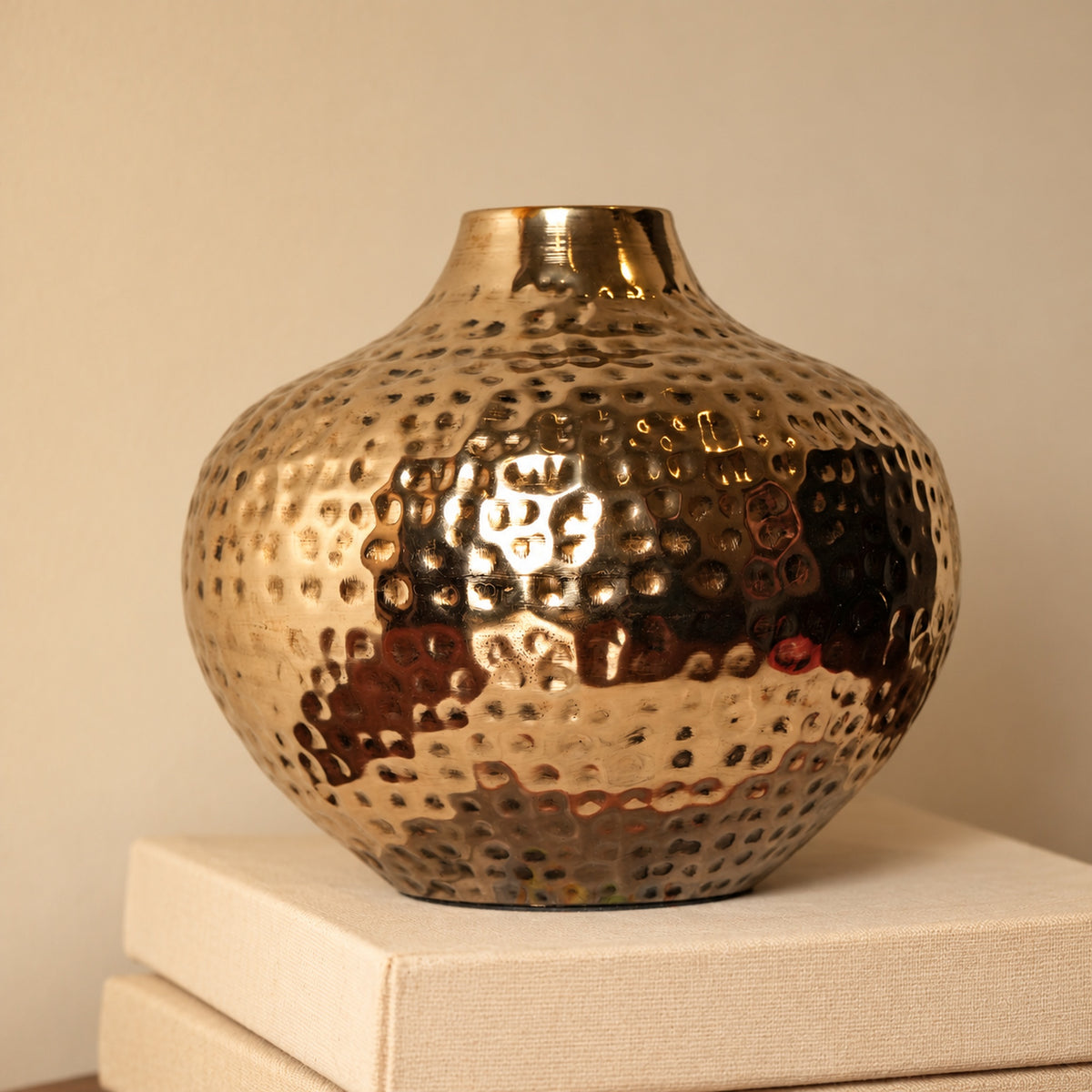 Oria 7 inch hammered champagne gold globe vase on a stack of cream books