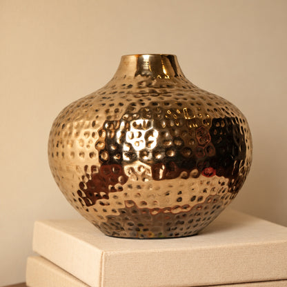 Oria 7 inch hammered champagne gold globe vase on a stack of cream books