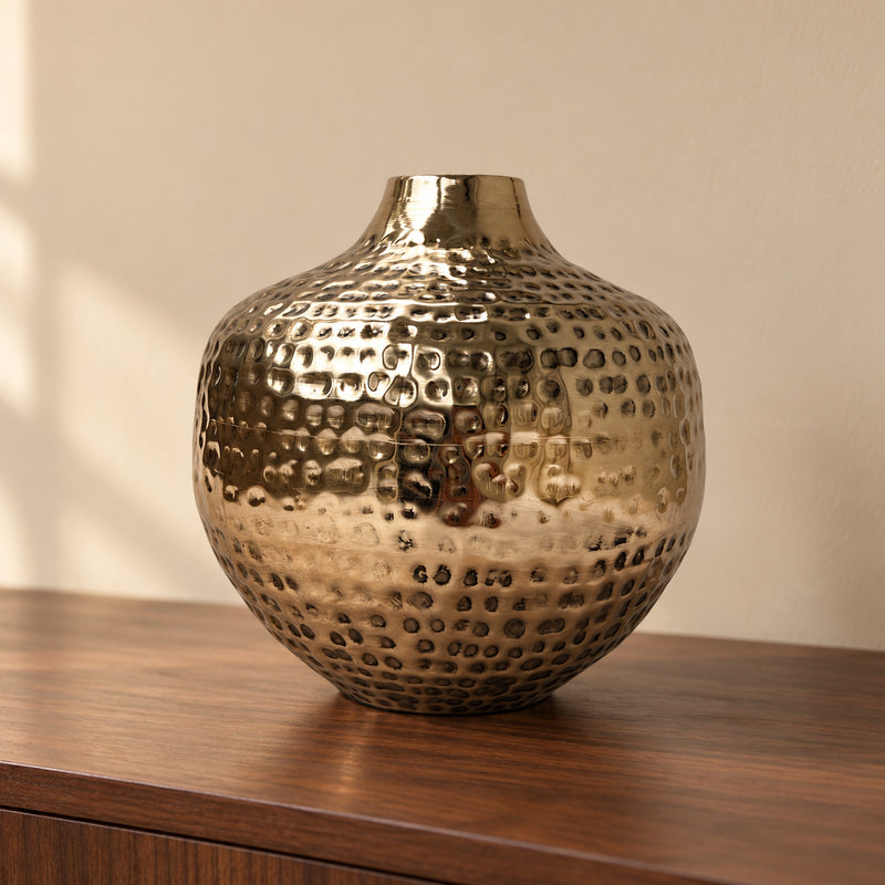 Oria 8 inch hammered champagne gold globe vase on a walnut console against a cream wall