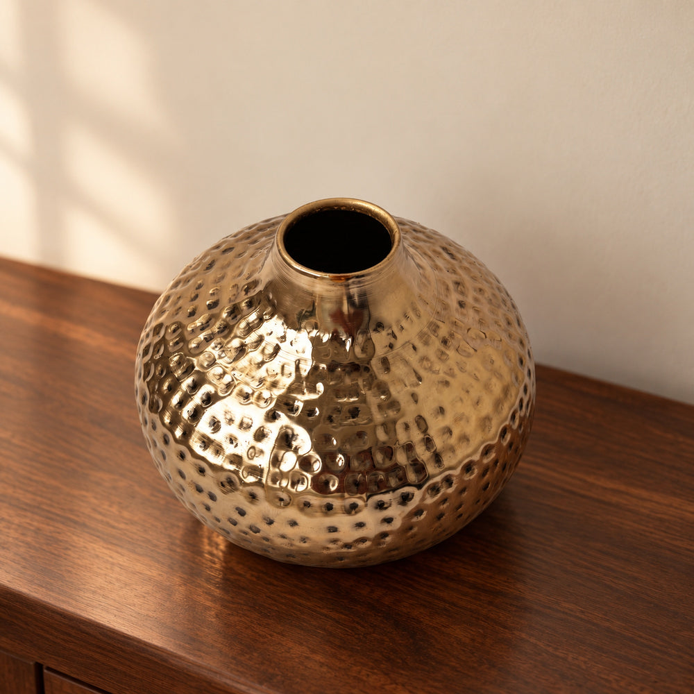 Oria 7 inch hammered champagne gold globe vase on a walnut console in warm light