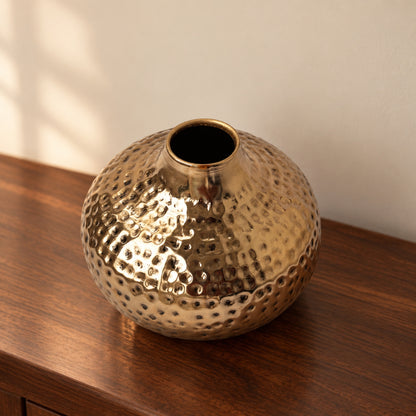 Oria 7 inch hammered champagne gold globe vase on a walnut console in warm light