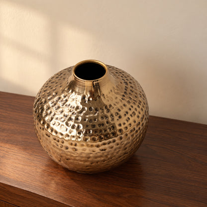 Oria 8 inch hammered champagne gold globe vase seen from slightly above on a walnut console