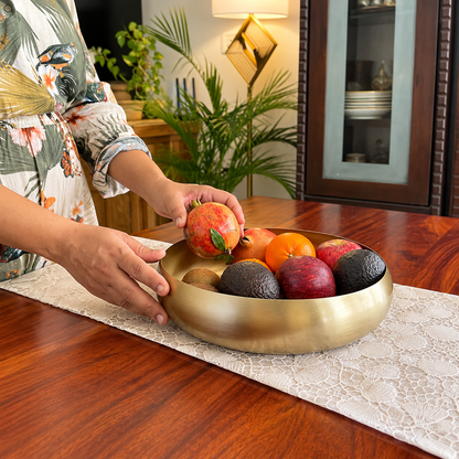 Hand placing a fruit in the Ekam Metal Urli