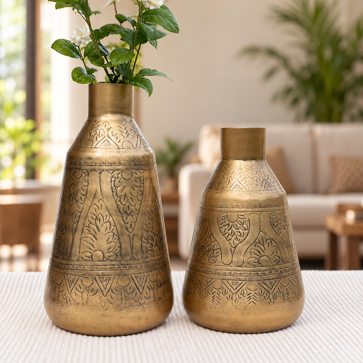 Aurum 15 inch and 12 inch antique brass finish vases together in a living room, one with jasmine flowers