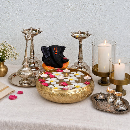 Chitra urli on a pooja table with brass lamps and flowers
