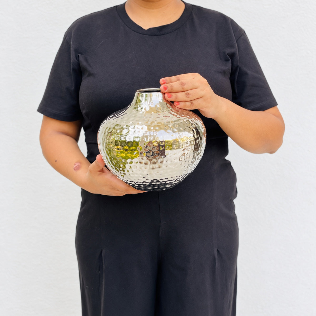 Person holding the Oria 7 inch hammered silver globe vase in both hands to show its size